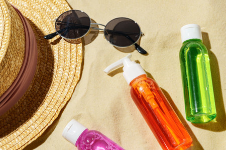 Colorful Sunscreen Bottles Arranged on Sandy Beach With Summer Essentialsの写真素材