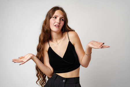 Young Woman Shrugging and Looking Confused Against White Backgroundの写真素材