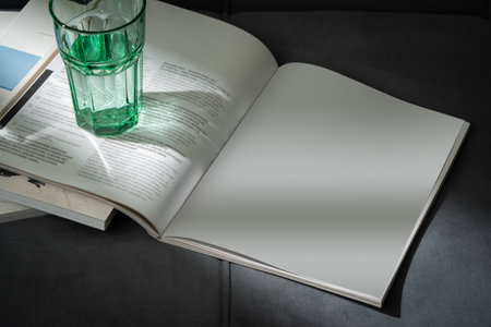 Glass of Water on Open Magazines Resting on a Couchの写真素材