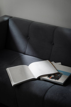 Stack of Magazines on a Black Leather Couch in Soft Lightの写真素材