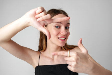 Young Woman Framing a Scene With Her Hands Against a White Backgroundの写真素材