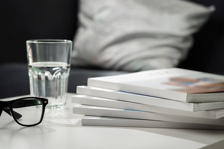 Eyeglasses with stack of books, and the glass of water on the tableの写真素材