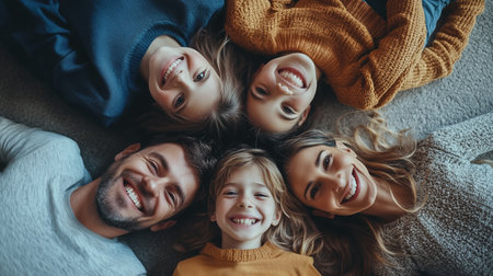 A joyful family sharing laughter and smiles while lying on a cozy carpet in a warm living room during a sunny afternoonの素材