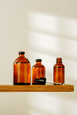 Collection of Amber Glass Dropper Bottles Displayed on a Minimalist White Surface in Natural Lightの写真素材
