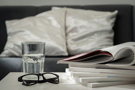 Eyeglasses with stack of books, and the glass of water on the table