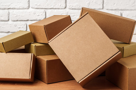 Stacked Cardboard Boxes Against A White Brick Wallの写真素材