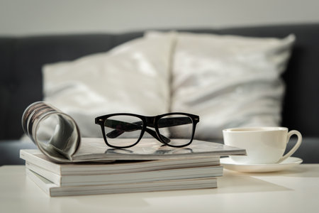A Cup of Coffee, Glasses, and a Stack of Magazines on a White Tabletop