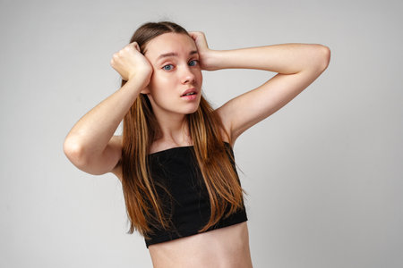 Young Woman With Long Brown Hair Holds Her Head in Shockの写真素材