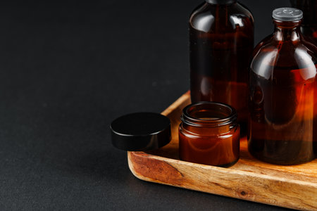 Collection of amber glass bottles arranged on a wooden tray against a dark backgroundの写真素材