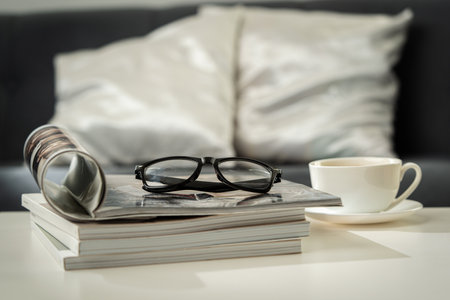 A Cup of Coffee, Glasses, and a Stack of Magazines on a White Tabletopの写真素材