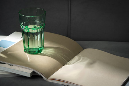 Glass of Water on Open Magazines Resting on a Couchの写真素材