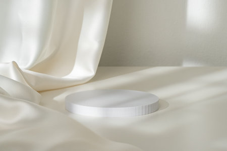 Modern Minimalist White Sculpture Displayed on Soft Draped Fabric in Natural Lightの写真素材