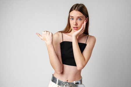 Young Woman Pointing to copy space in studioの写真素材