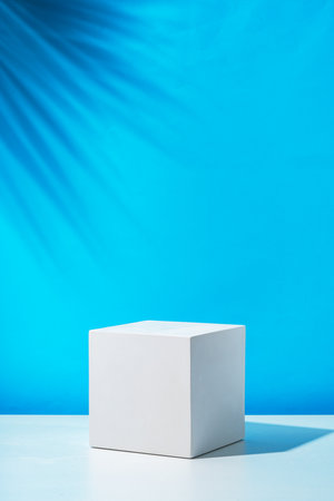 A clean white cube positioned on a minimalist surface against a vibrant blue backdropの写真素材