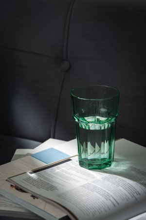 Glass of Water on Open Magazines Resting on a Couchの写真素材