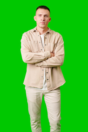 Young Man Standing Against a Bright Green Background in Casual Clothingの写真素材