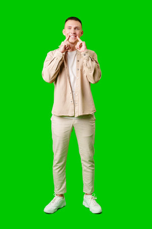 Young Man Smiling and Making Funny Expressions on Bright Green Background in Studioの写真素材