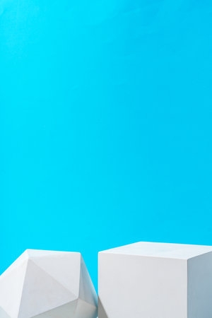 Two geometric shapes on display against a bright blue background in a modern settingの写真素材
