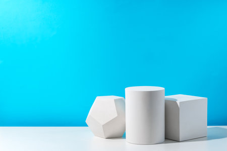 Three geometric shapes arranged on a table against a bright blue background during daytime lightingの写真素材