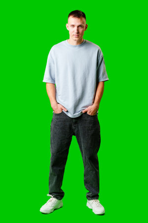 Young Man Standing Confidently Against Bright Green Background in Casual Attireの写真素材