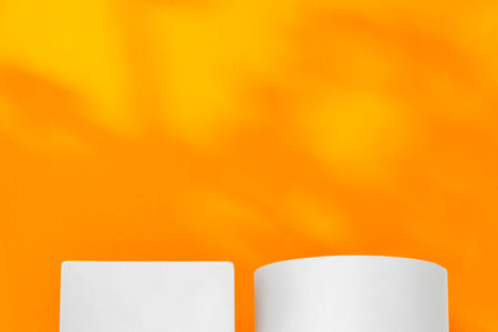 White geometric shapes on a vibrant orange background with soft shadows in a well-lit indoor settingの写真素材