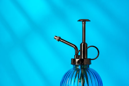 Glass spray bottle with a metallic nozzle against a bright blue backgroundの写真素材