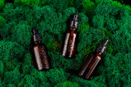 Brown glass dropper bottles arranged on green moss in a natural settingの写真素材