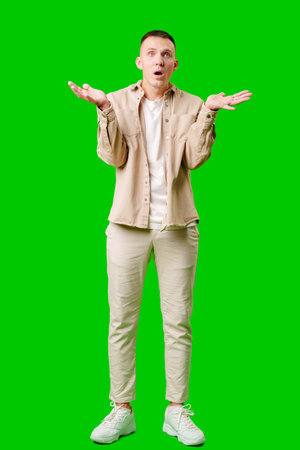 Cheerful Young Man Posing With Outstretched Hands Against a Bright Green Backgroundの写真素材
