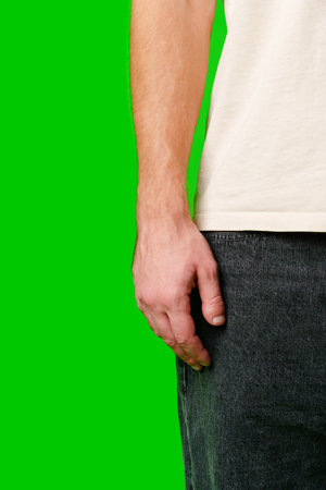 A Close-Up View of a Mans Hand Near His Pocket Against a Bright Green Backgroundの写真素材