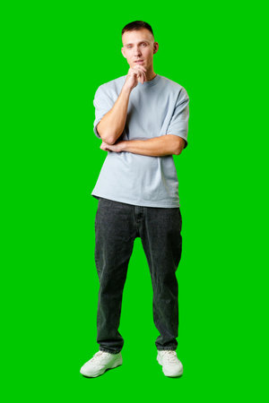 Young Man Standing Confidently Against Bright Green Background in Casual Attireの写真素材