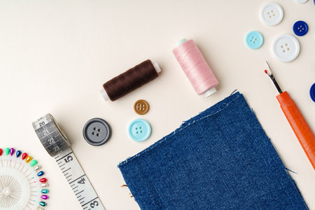 Sewing supplies and denim fabric arranged on a workspace for clothing alterations in a bright settingの写真素材