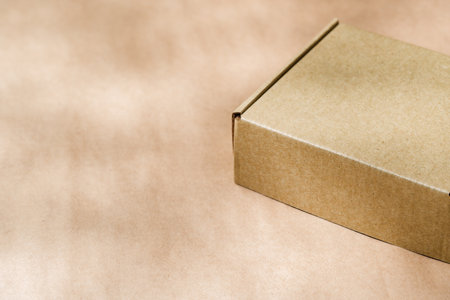 A plain cardboard box on a textured surface with soft light and shadows during the afternoonの写真素材