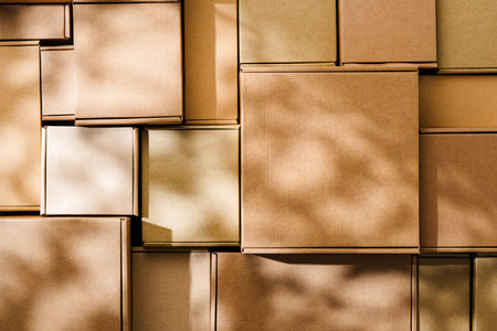 Stacked cardboard boxes arranged in a neat pattern under natural lightの写真素材