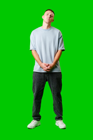 Young Man Standing Confidently Against Bright Green Background in Casual Attireの写真素材