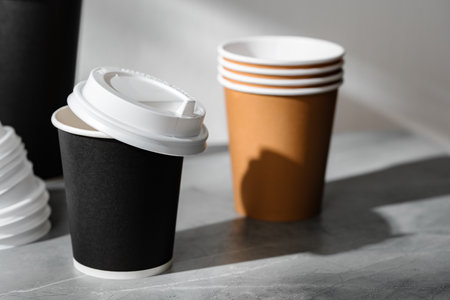 Stack of coffee cups in various colors with lids on a gray surfaceの写真素材