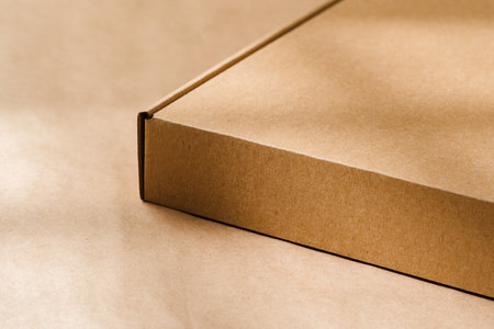 A plain cardboard box on a textured surface with soft light and shadows during the afternoonの写真素材