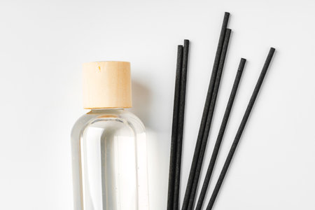 A minimalist display of essential oil and black diffuser sticks on a clean white backgroundの写真素材