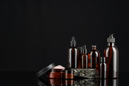 Collection of amber glass bottles arranged on a dark reflective surface, showcasing various shapes and sizesの写真素材