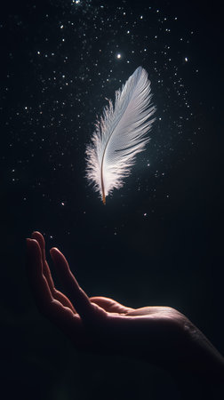 A delicate feather floating above an open hand against a starry night backgroundの素材