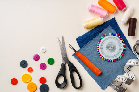 Sewing supplies and denim fabric arranged on a workspace for clothing alterations in a bright settingの写真素材