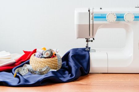 Sewing tools and materials arranged on fabric with a sewing machine in a bright workspace
