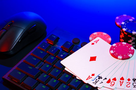 A vibrant arrangement of poker chips and playing cards on a gaming keyboard with a mouse at an...