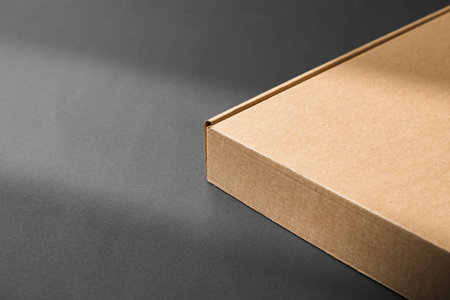 A cardboard box casting shadows on a dark surfaceの写真素材