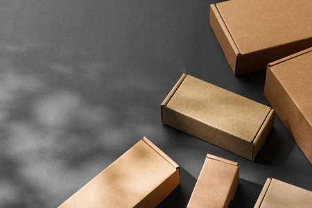 Various sizes of brown cardboard boxes arranged on a black surface with soft lighting effects during...