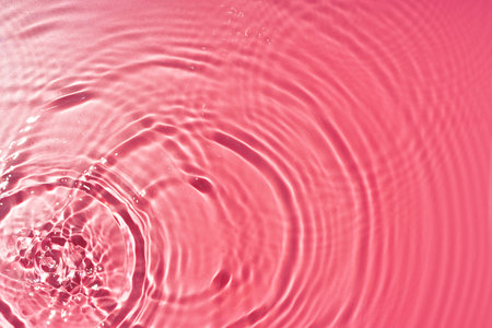 Ripples of light and color in a pink water surface reflecting mesmerizing patterns at middayの写真素材