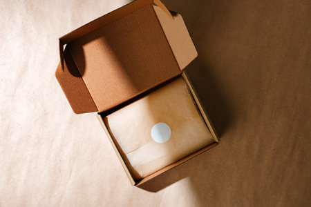A sealed kraft box containing a wrapped item, positioned on a textured brown surface for an unboxing experienceの写真素材