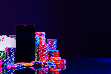 Brightly colored poker chips and playing cards arranged near a smartphoneの写真素材