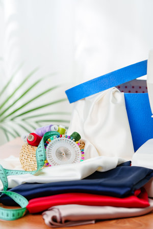 Crafting supplies arranged on a wooden table with colorful threads, measuring tape, and fabric in a well-lit workspaceの写真素材