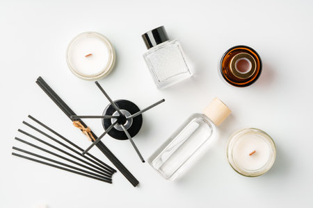 Aromatic essentials including scented candles, incense sticks, and diffusers arranged on a light backgroundの写真素材