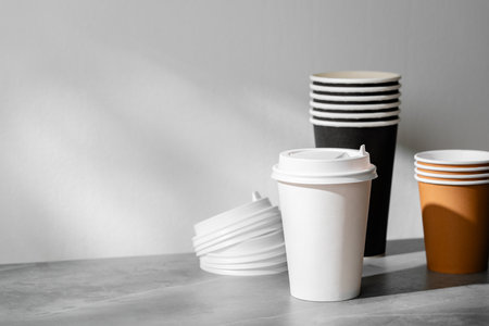 Stack of coffee cups in various colors with lids on a gray surfaceの写真素材